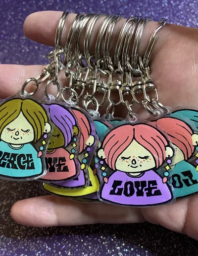 Porte clés représentant des dames avec des boucles d'oreilles et des t-shirt avec écrit Peace ou Love.